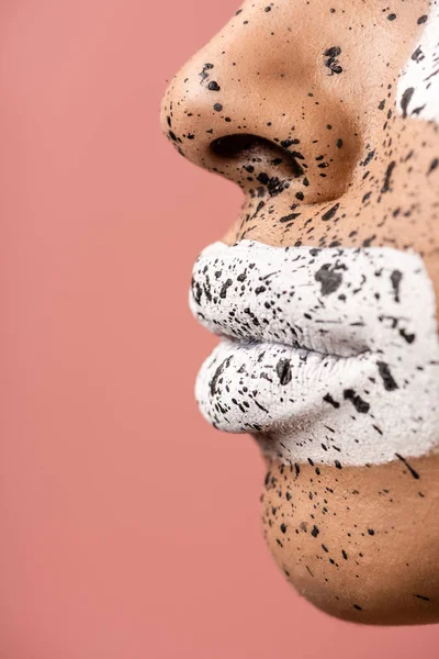Primo piano vista delle labbra femminili con vernice bianca e viso con spruzzi marroni isolati su rosa — Foto stock