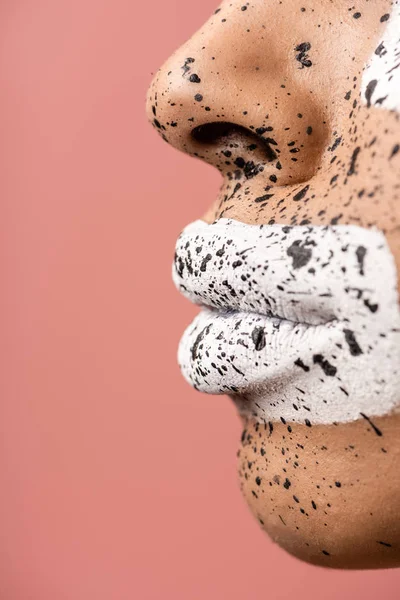 Vue rapprochée des lèvres féminines avec peinture blanche et du visage avec éclaboussures brunes isolées sur rose — Photo de stock