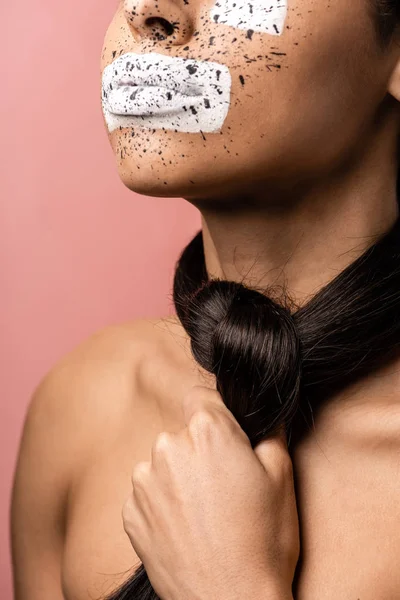 Corte tiro de jovem afro-americana com tinta no rosto e cabelo morena em torno do pescoço isolado em rosa — Fotografia de Stock