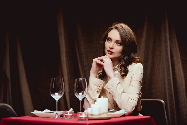 Belle femme coûteuse assise à table et attendant quelqu'un au restaurant — Photo de stock