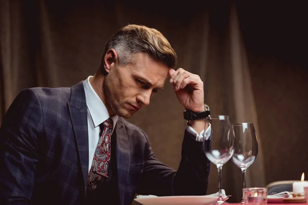 Handsome pensive man sitting at table and waiting for someone in restaurant — Stock Photo