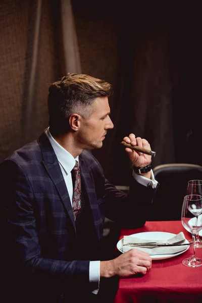 Handsome man in formal wear smoking cigar in restaurant — Stock Photo