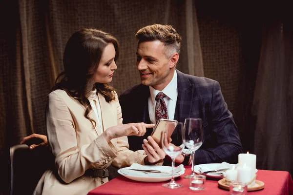 Couple sitting at table and using smartphone during romantic date in restaurant — Stock Photo