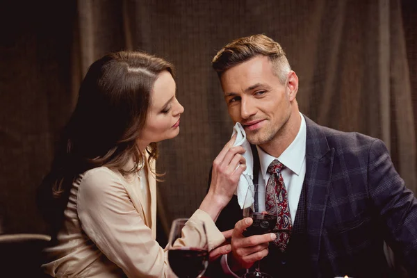 Woman wiping face of handsome man with handkerchief during romantic date in restaurant — Stock Photo