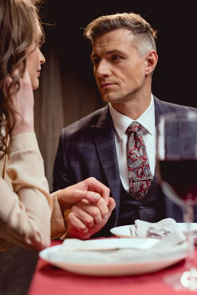 Selective focus of couple holding hands while having romantic date in restaurant — Stock Photo