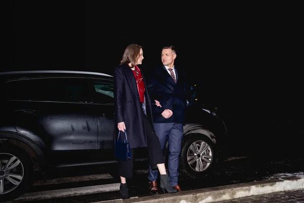 Paar hält Händchen und schaut sich mit Auto im Hintergrund an — Stockfoto