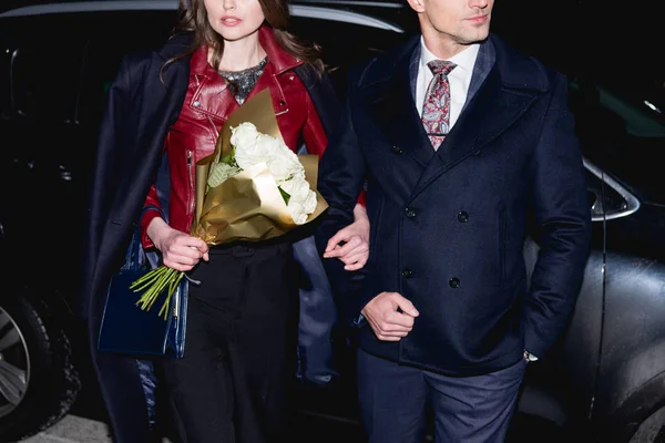Vue recadrée de la femme avec bouquet de fleurs tenant la main avec l'homme — Photo de stock
