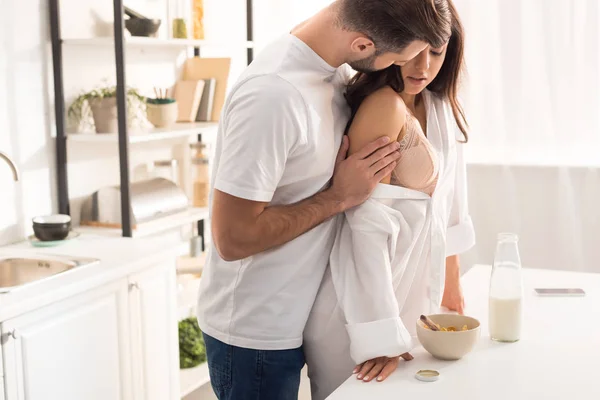 Homem apaixonadamente abraçando mulher durante o café da manhã em casa — Fotografia de Stock