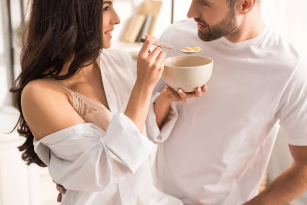 Mujer alimentando al hombre con cereales durante el desayuno por la mañana - foto de stock