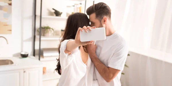 Pareja en ropa blanca tomando selfie en el teléfono inteligente en casa — Stock Photo