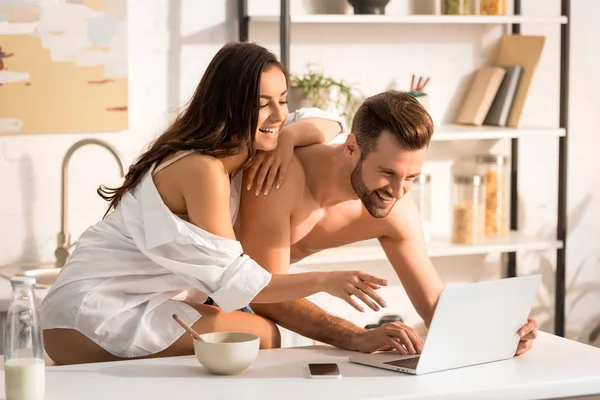 Beautiful sexy couple using laptop during breakfast at home — Stock Photo