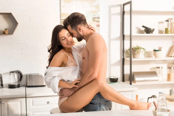 Jovem casal sedutor abraçando na cozinha em casa — Fotografia de Stock