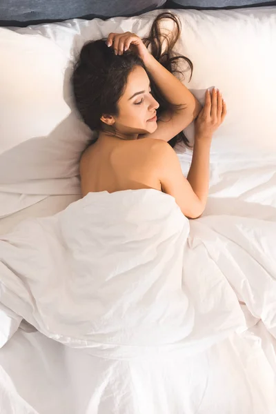 Vista superior de la hermosa mujer desnuda durmiendo en la cama en casa por la mañana - foto de stock