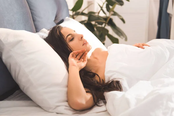 Hermosa mujer durmiendo en la cama en casa por la mañana - foto de stock