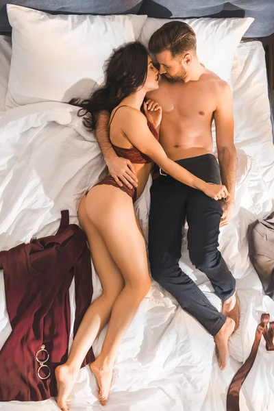 Hermosa mujer sexy en lencería roja acostado con el hombre en la cama - foto de stock