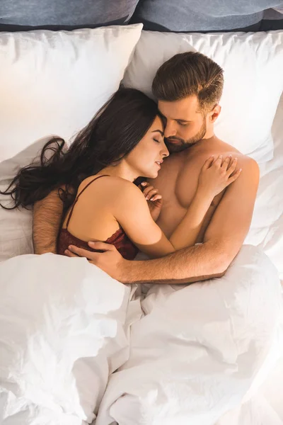 Schönes junges Paar, das sich umarmt, während es im Bett schläft — Stockfoto