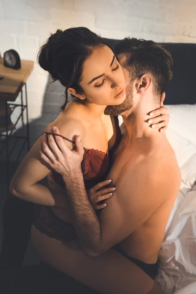 Beautiful sexy couple passionately embracing on bed at home — Stock Photo