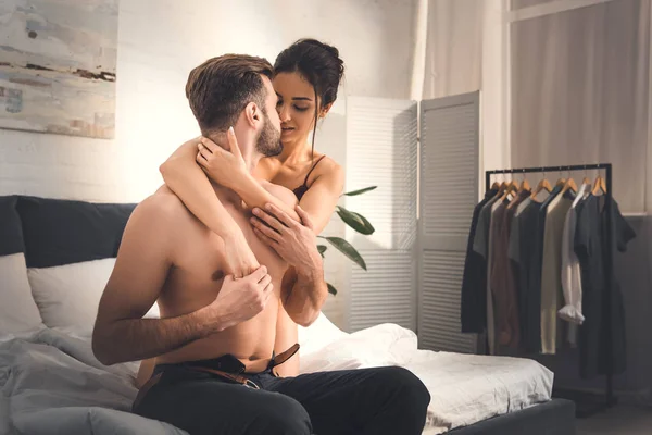 Selective focus of woman embracing shirtless man on bed at home — Stock Photo