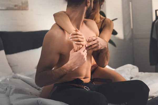 Partial view of woman embracing shirtless man on bed at home — Stock Photo