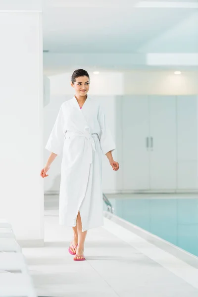 Attractive woman in bathrobe walking near swimming pool — Stock Photo