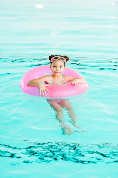 Cheerful child learning swimming with inflatable ring in swimming pool — Stock Photo
