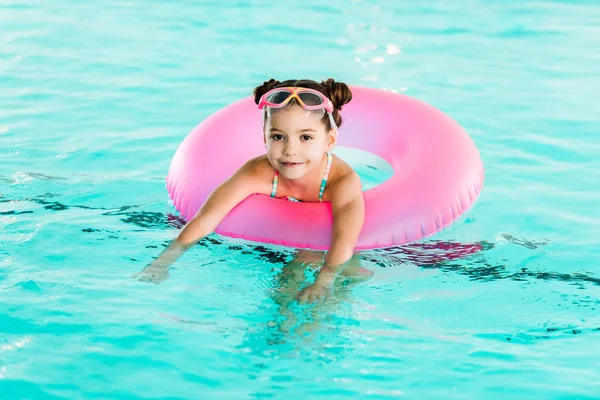 Усміхнена дитина вчиться плавати з надувним кільцем у басейні — стокове фото