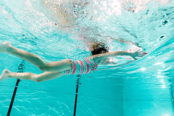 Дитина плаває у блакитній воді в басейні — стокове фото