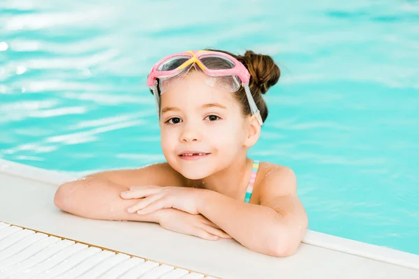 Adorable kid in googles swimming near poolside in swimming pool — Stock Photo