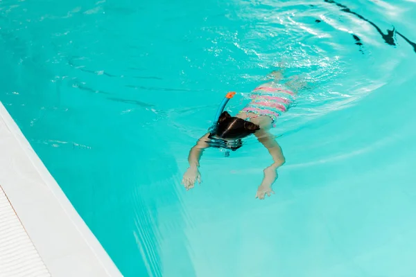 Child snorkeling in blue water in swimming pool — Stock Photo