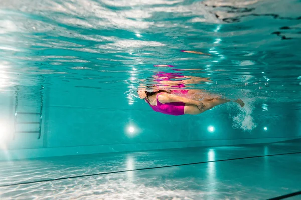 Жінка плаває у блакитній воді в басейні — стокове фото