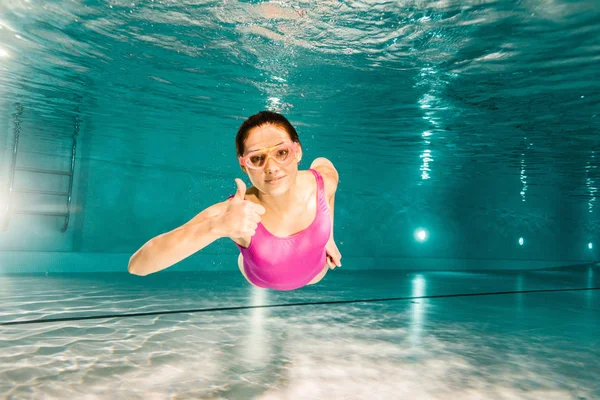 Mujer feliz mostrando el pulgar hacia arriba mientras bucea bajo el agua - foto de stock