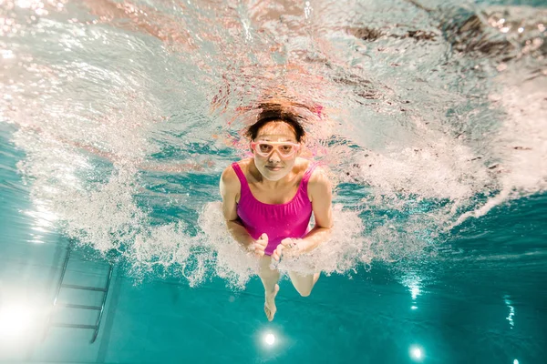 Жінка занурюється в окуляри під водою в басейні — стокове фото