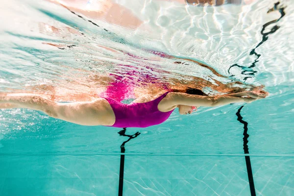 Жінка плаває під водою в басейні з блакитною водою — стокове фото