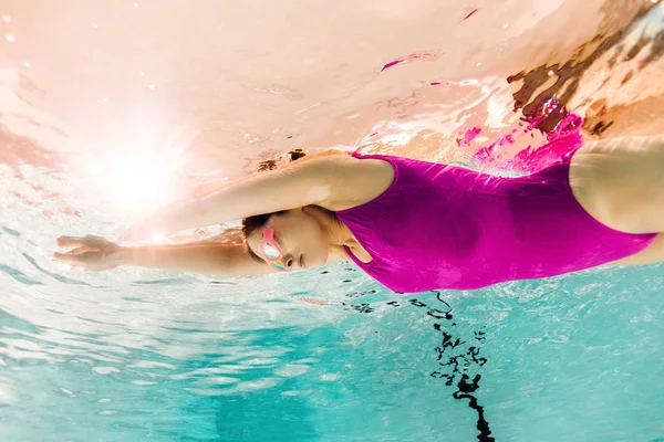 Зосереджена жінка плаває в окулярах під водою в басейні — стокове фото
