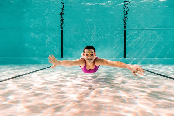 Mujer feliz en googles buceando bajo el agua en la piscina - foto de stock