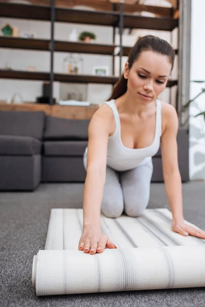 Messa a fuoco selettiva della donna tappeto fitness rotolamento per praticare yoga a casa — Foto stock