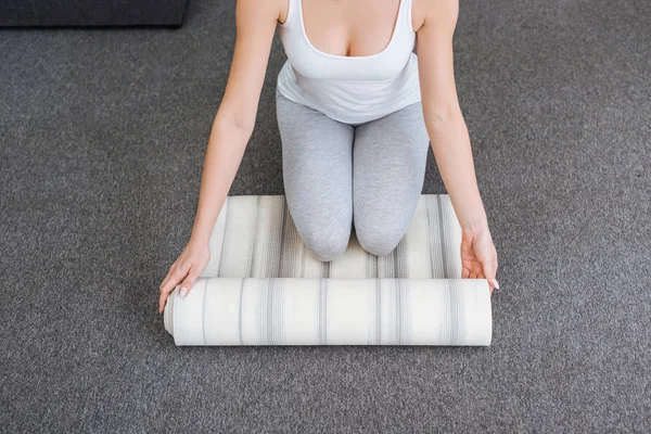 Abgeschnittene Ansicht einer Frau, die Fitnessmatte rollt, um zu Hause Yoga zu praktizieren — Stockfoto