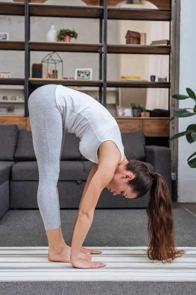 Junge Frau übt Big Zeh Pose zu Hause im Wohnzimmer — Stockfoto