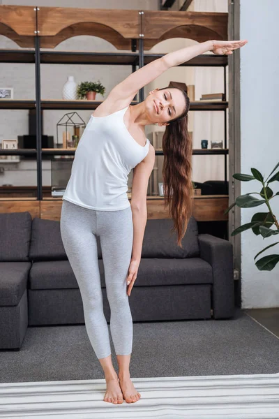 Jovem fazendo exercício de alongamento em casa na sala de estar — Fotografia de Stock