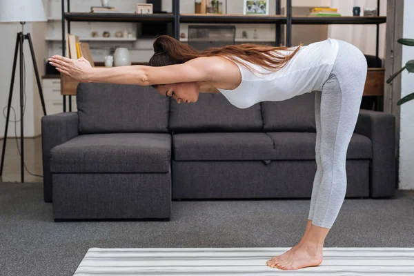 Joven mujer practicando yoga pose en casa en sala de estar - foto de stock
