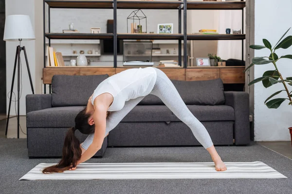 Joven mujer practicando intensa postura de estiramiento lateral en casa en la sala de estar - foto de stock
