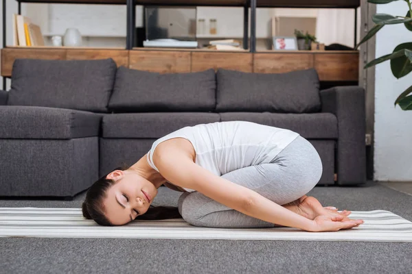 Mujer haciendo ejercicio de relajación en casa en la sala de estar - foto de stock
