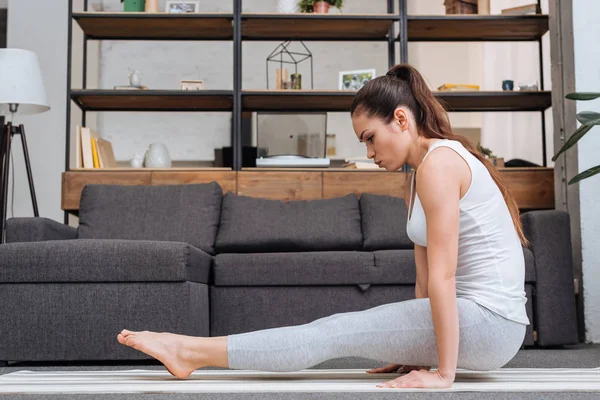Joven mujer practicando yoga pose en casa en sala de estar — Stock Photo
