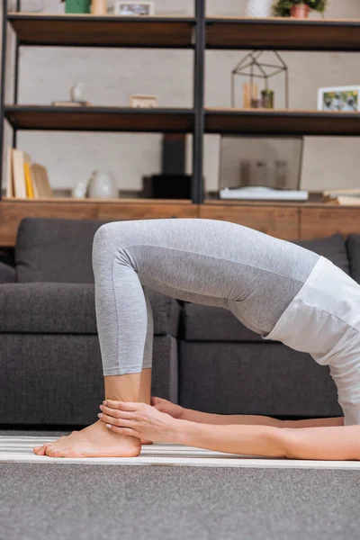 Cropped view of woman practicing bridge pose at home in living room — Stock Photo