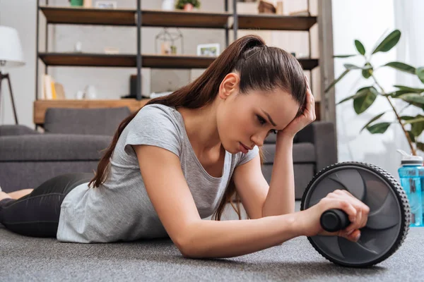 Exhausted sportswoman training with ab wheel at home — Stock Photo