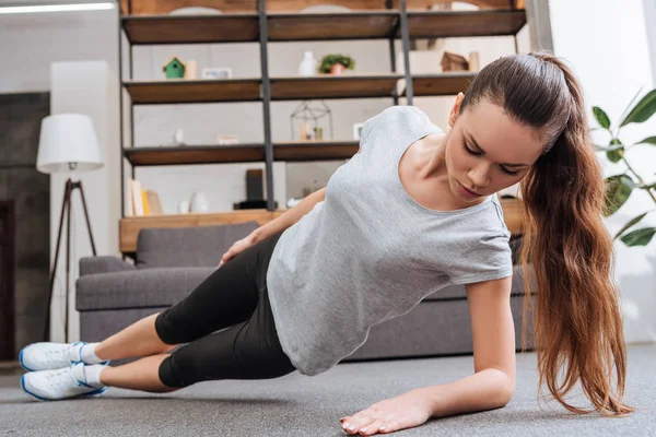 Selective focus of sportswoman doing side plank exercise at home — Stock Photo