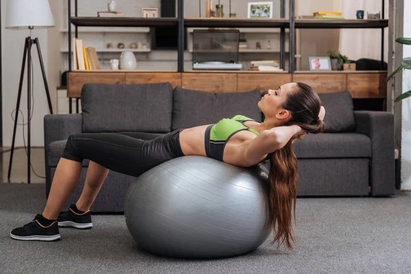 Fokussierte Sportlerin trainiert zu Hause mit Fitnessball — Stockfoto