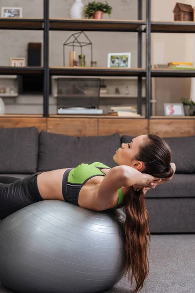 Enfoque selectivo de la deportista enfocada ejercicio con pelota de fitness en casa - foto de stock