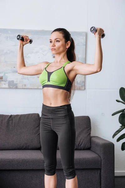 Schöne konzentrierte Sportlerin beim Training mit Kurzhanteln zu Hause — Stockfoto