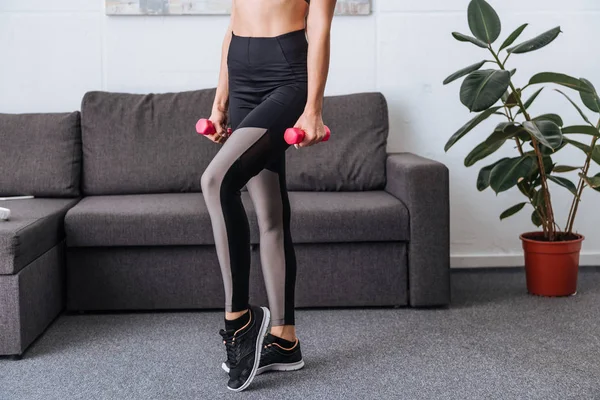 Partial view of sportswoman with dumbbells at home — Stock Photo